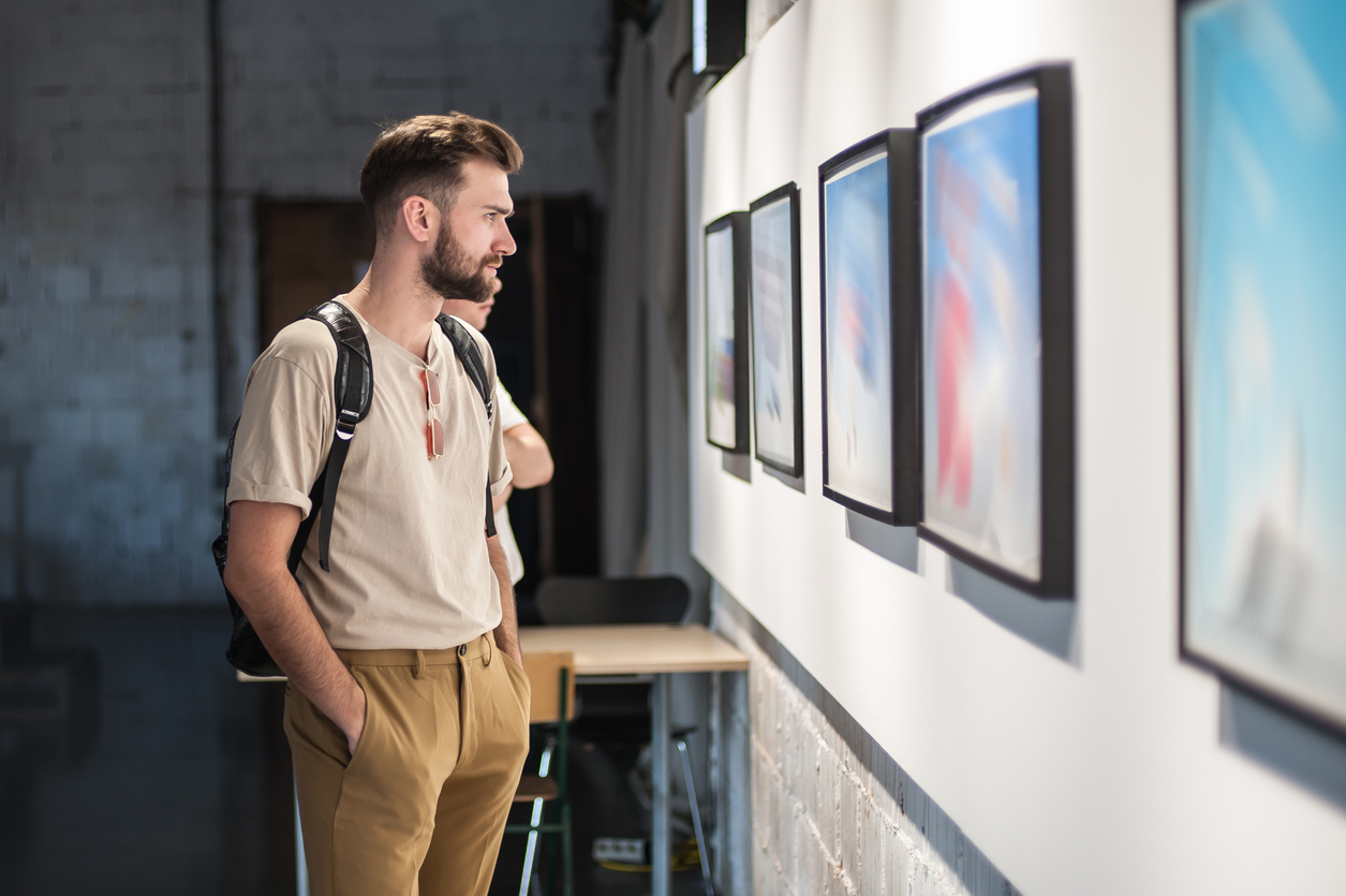 Young man in modern art exhibition gallery hall